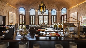 A spacious breakfast area with a high arched ceiling, large windows, and a variety of breakfast items and beverages. - Hilton San Luis Potosi (San Luis Potosi)