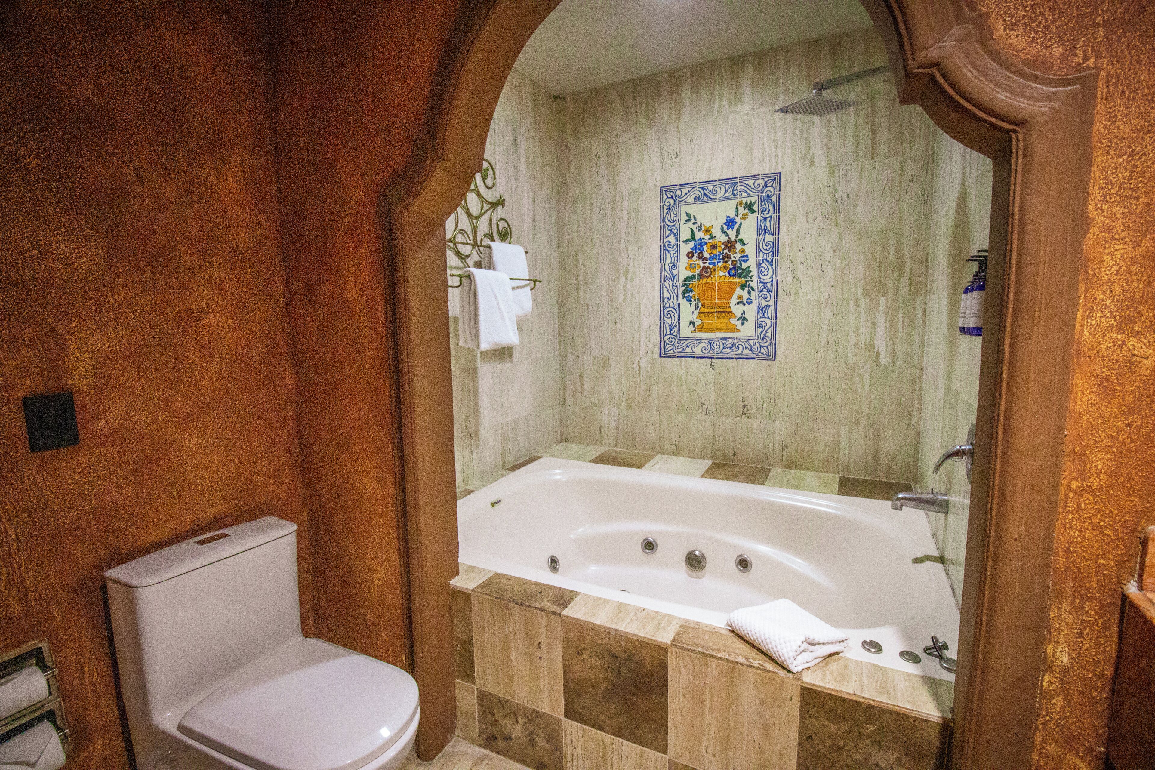 A bathroom with a bathtub, a toilet, and a shower area.