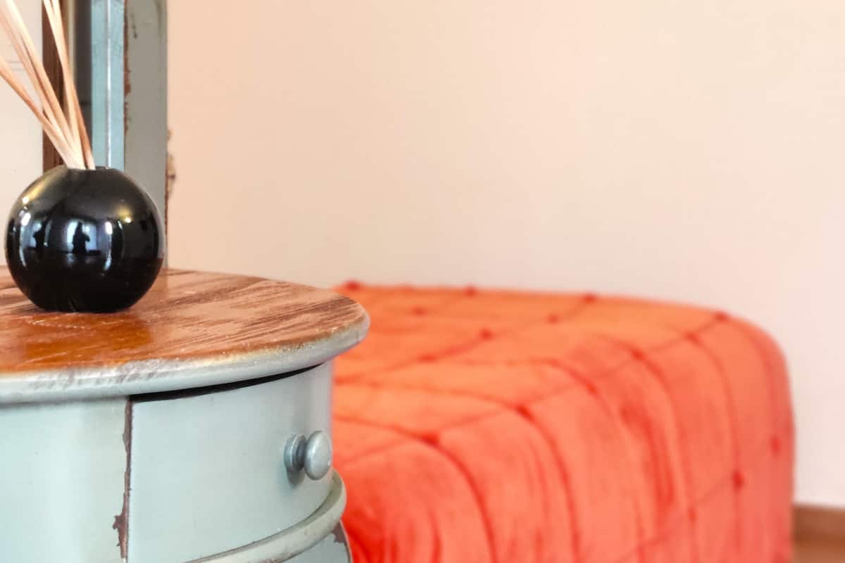 Une pièce comprenant un lit, une petite table avec un vase et deux tableaux encadrés accrochés au mur.