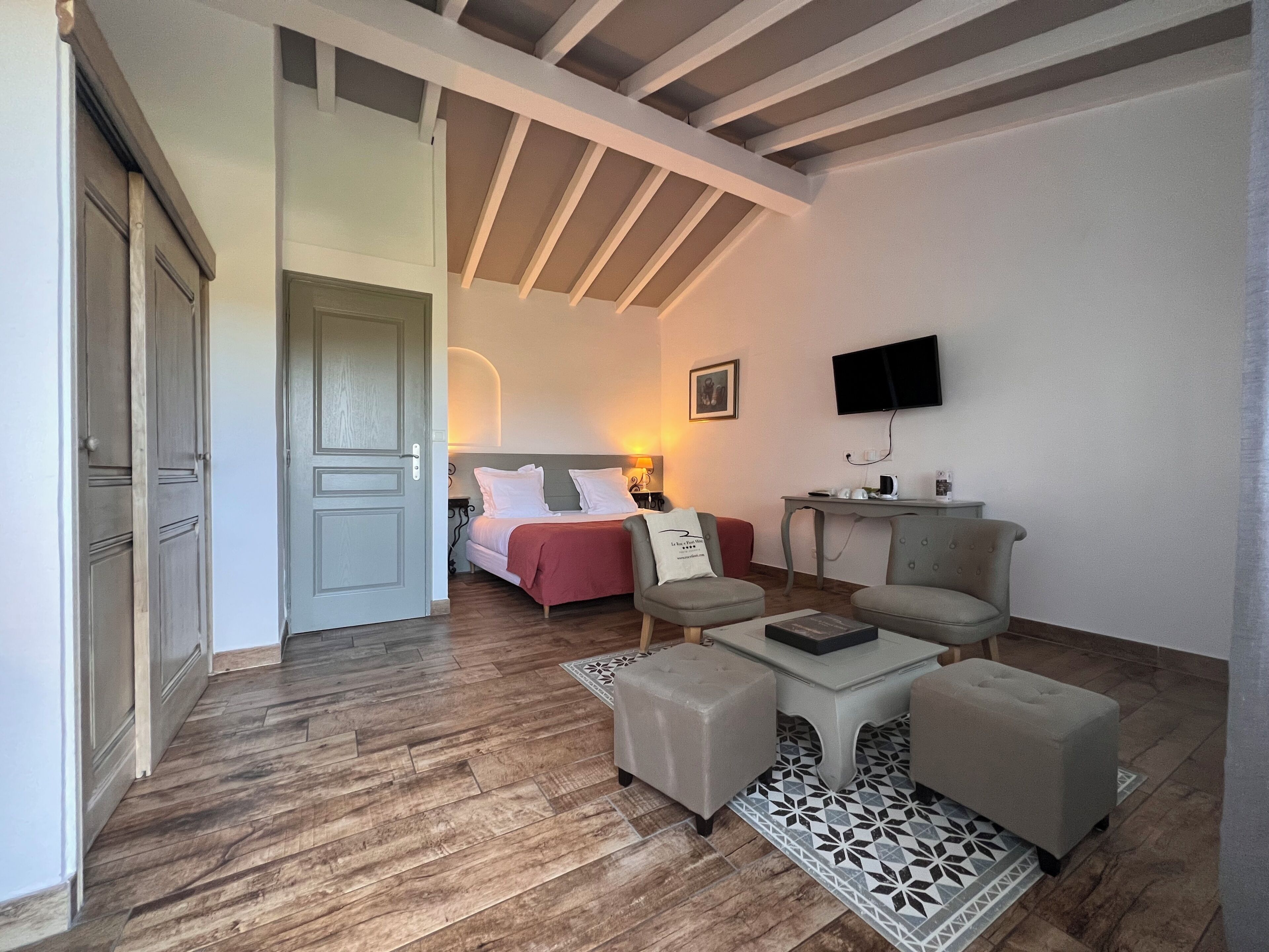 A room with a bed, two armchairs, a coffee table, a TV, and a desk with a chair.