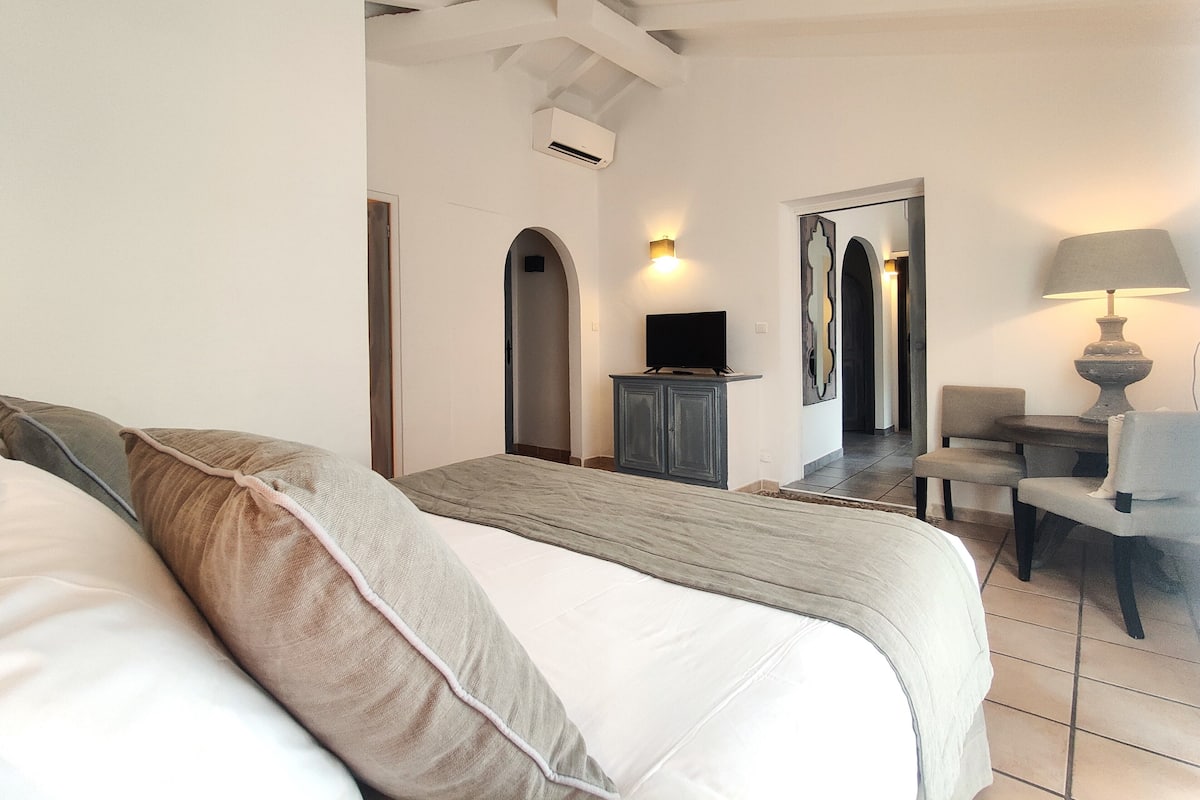 Une chambre d’hôtel avec un lit, un téléviseur posé sur un meuble, un bureau avec une chaise et une lampe.