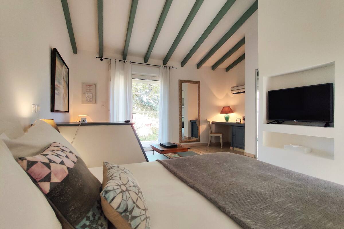 Une chambre d’hôtel avec un lit, un bureau et une chaise, une télévision et une fenêtre avec des rideaux.