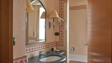 A bathroom with a sink, mirror, towel rack, and a shower area.