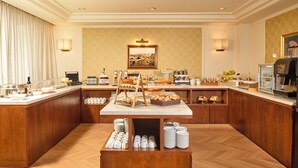 A hotel breakfast area with a buffet setup, including a variety of food items, a coffee machine, and a coffee press. - Hotel Perugia Plaza (Perugia)