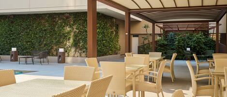 Un espace extérieur aménagé en terrasse, avec des meubles en osier et un coin salon abrité.