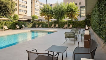 Una piscina al aire libre de temporada, sombrillas, tumbonas
