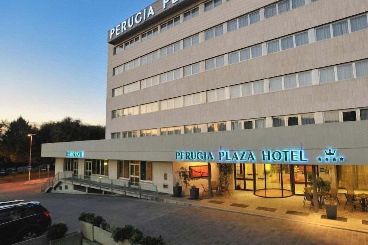 A hotel with a modern facade, a prominent entrance, and a well-lit outdoor seating area.