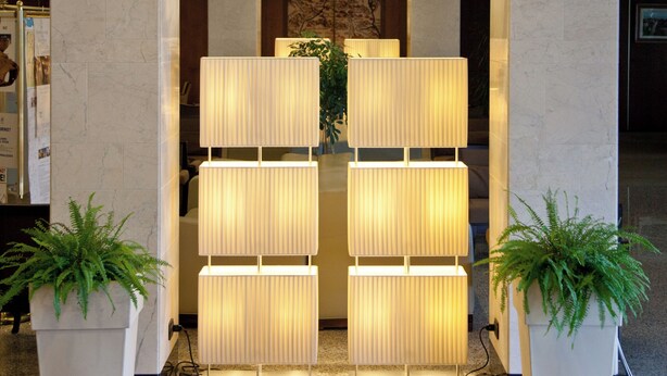 A lobby with marble columns, a reception desk, and a decorative light panel. - Hotel Perugia Plaza (Perugia)