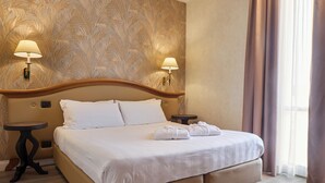 A hotel room with a large bed, two bedside tables, and a wall with a leaf pattern. - Hotel Perugia Plaza (Perugia)