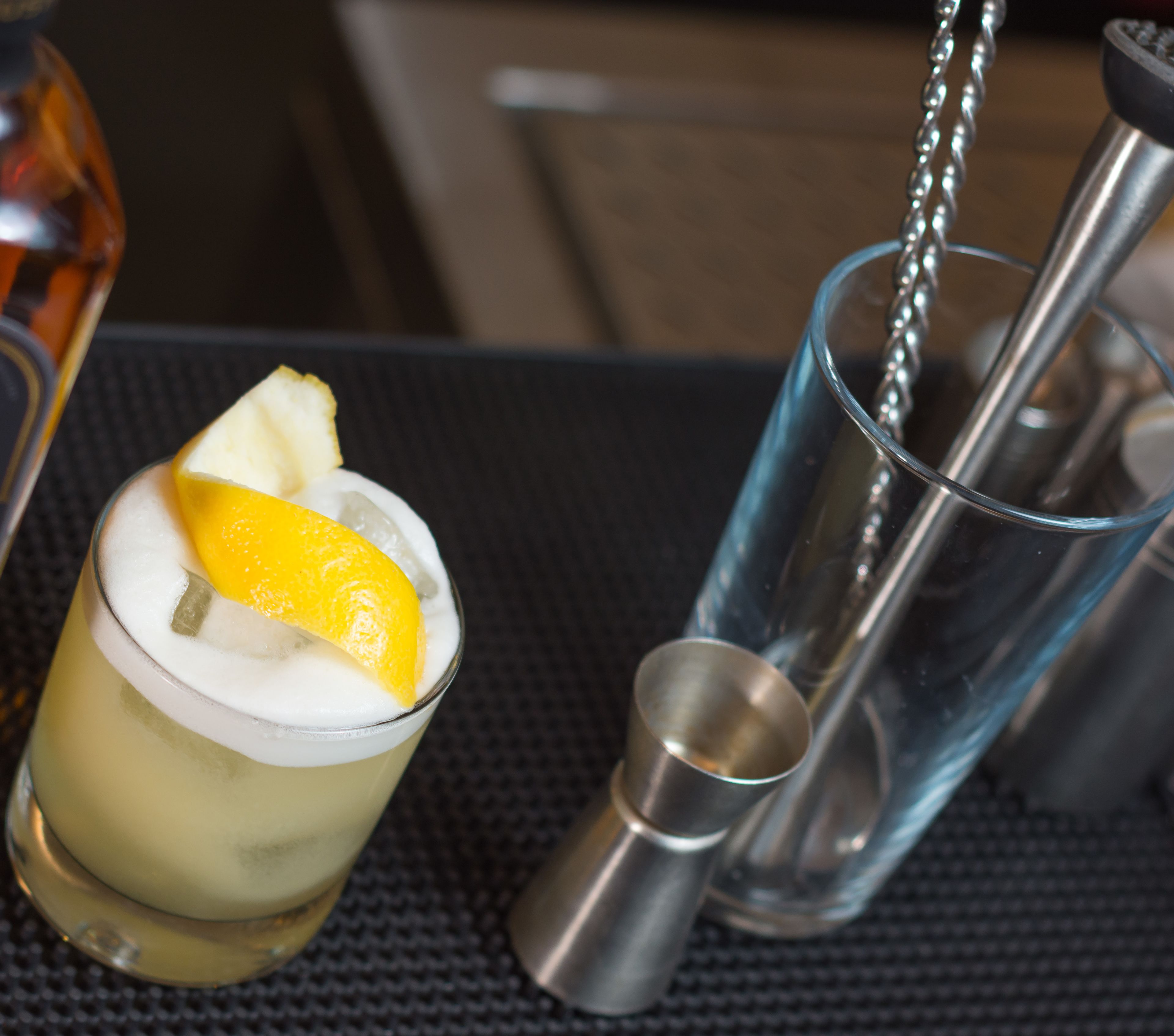 Un vaso de cóctel con una rodaja de limón sobre una mesa texturizada.