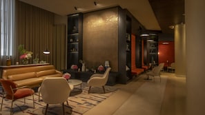 A modern lounge area with a sofa, chairs, a coffee table, and a decorative wall with shelves.
