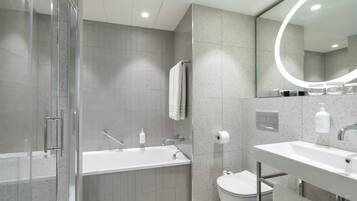 Un baño moderno con cabina de ducha de vidrio, bañera independiente, inodoro y tocador con espejo.