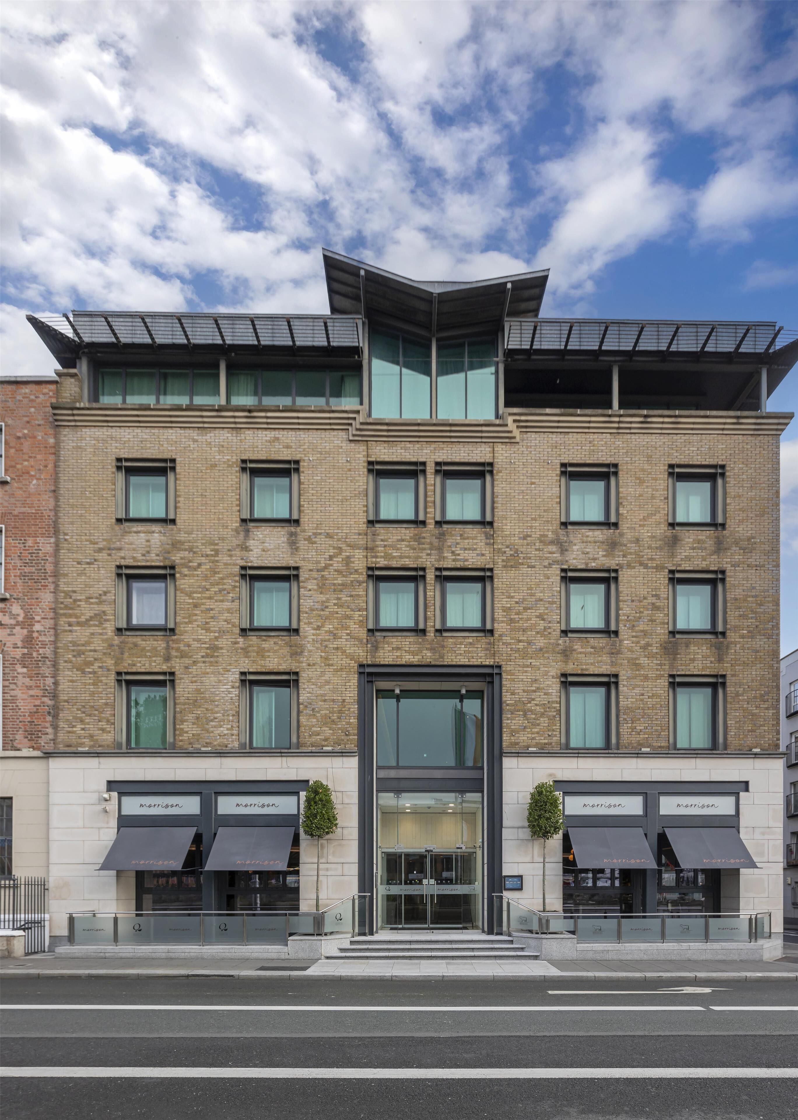 A modern building with a brick facade, multiple windows, and a glass entrance.