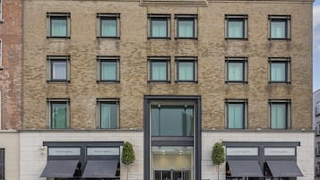 A modern building with a brick facade, multiple windows, and a glass entrance.