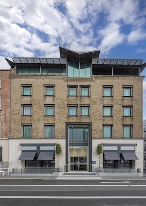 A modern building with a brick facade, multiple windows, and a glass entrance.