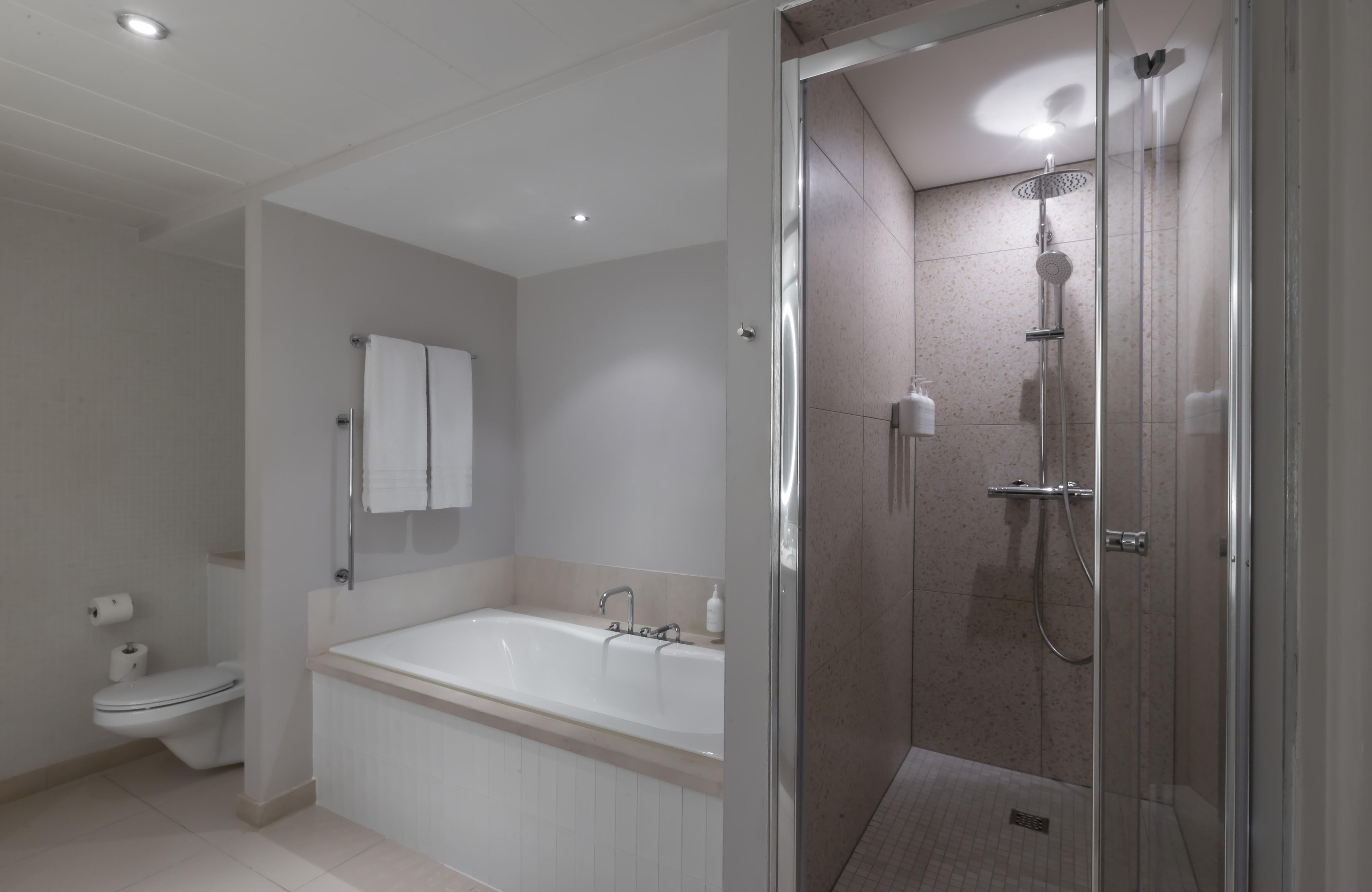 Et moderne badeværelse med badekar, bruser og toilet.