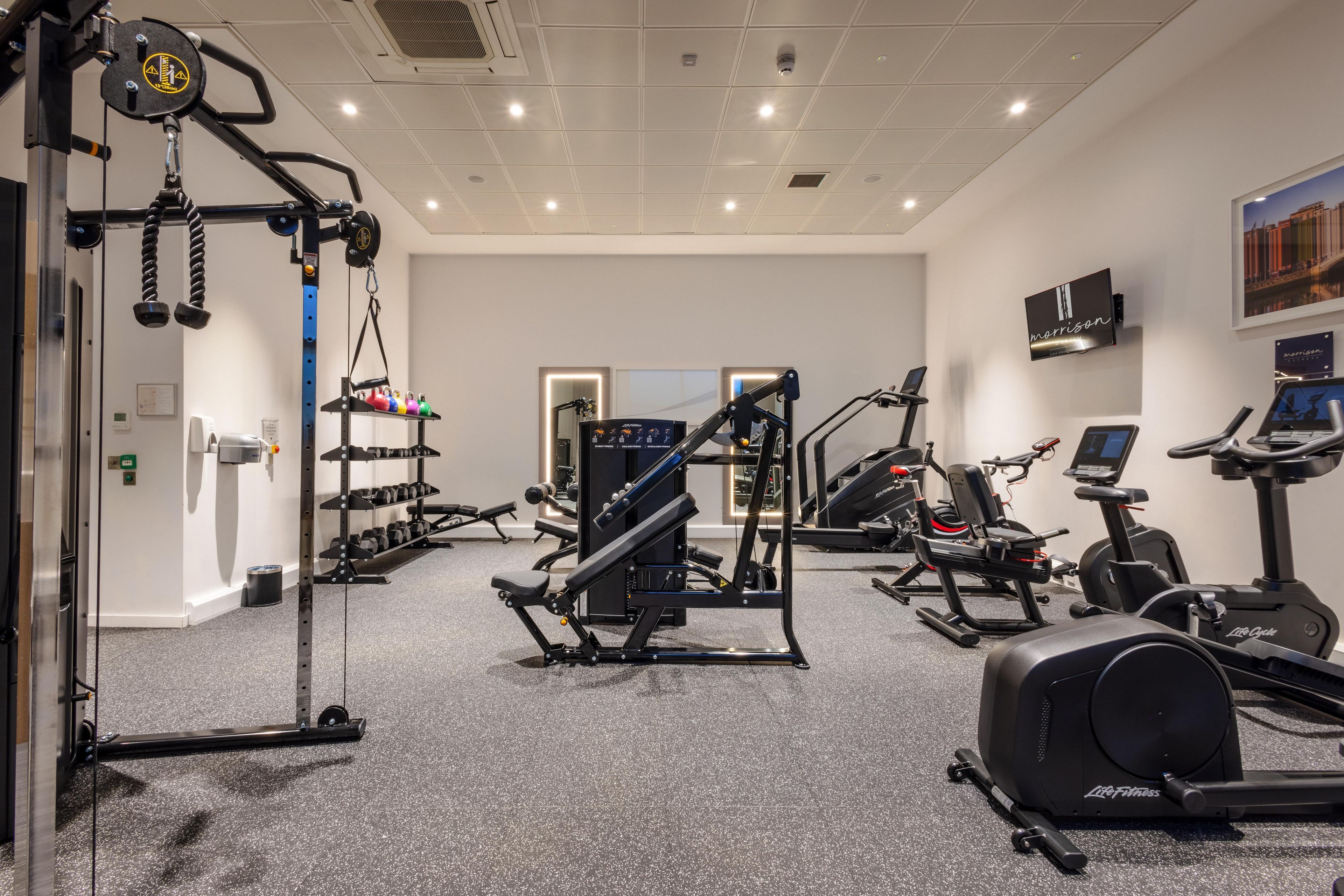 A gym with various exercise equipment, including treadmills, weight machines, and dumbbells.