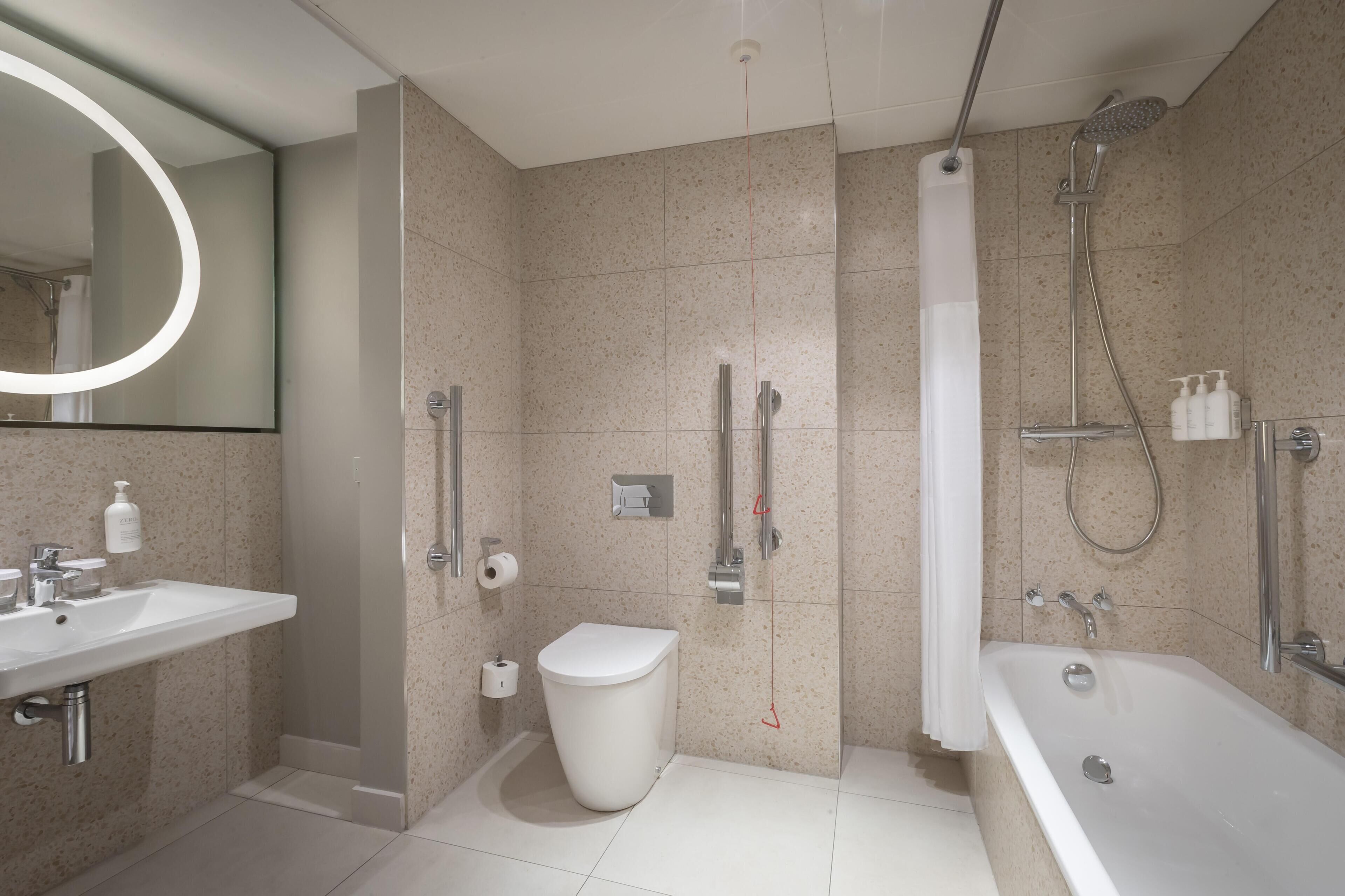 A modern bathroom with a sink, toilet, shower, and bathtub.