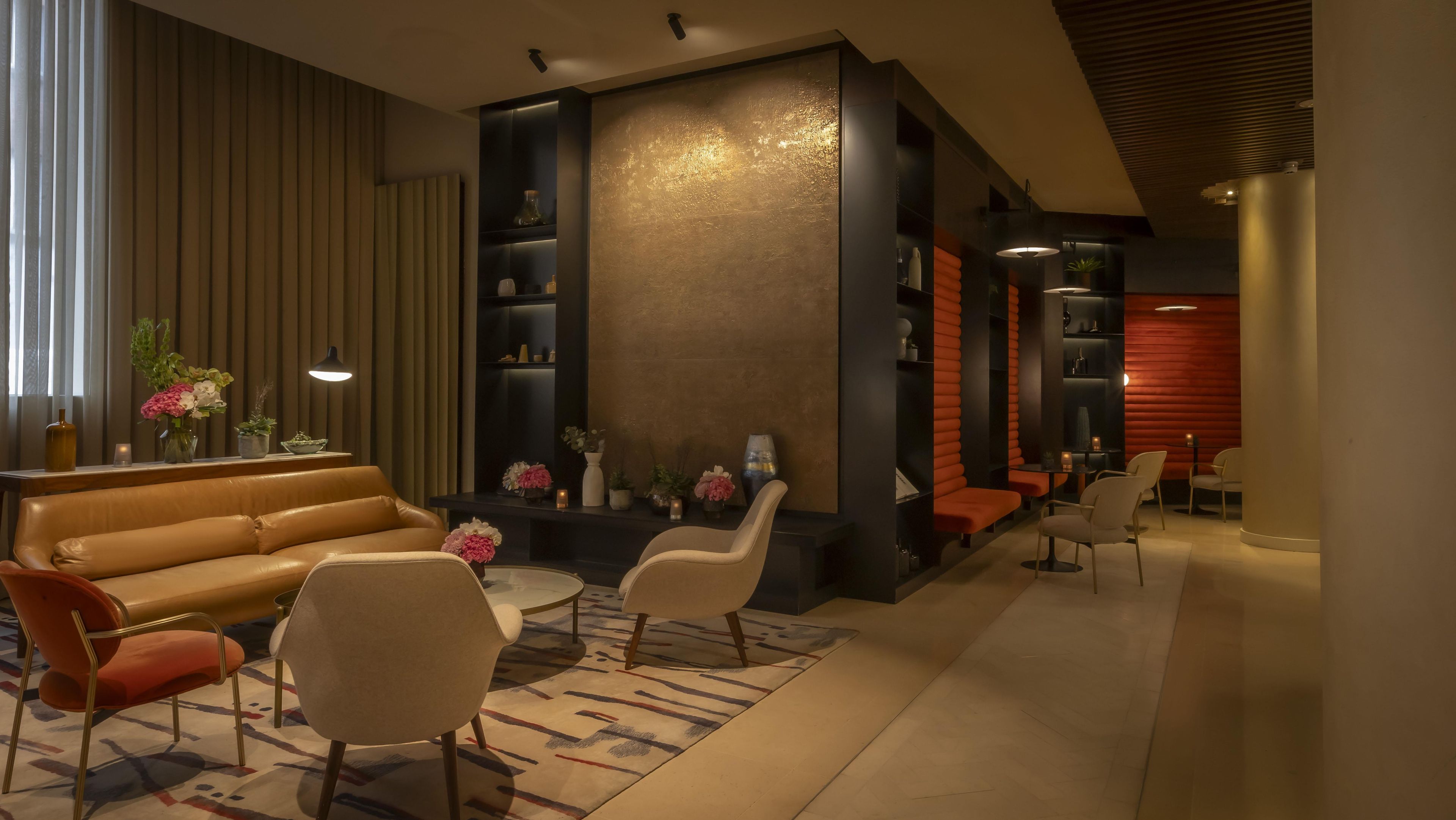 Uma área de estar moderna com sofá, cadeiras e um painel decorativo.