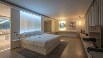 Un dormitorio moderno con una cama grande, mesitas de noche, un banco empotrado, zona de ducha y obras de arte en las paredes.