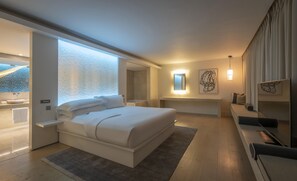 A modern bedroom with a large bed, bedside tables, a built-in bench, a shower area, and artwork on the walls.