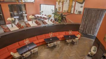 Una hall d'albergo moderna con un'area salotto dalle linee curve, diversi tavoli e una scala.