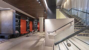 A modern interior with a staircase, a seating area with tables, and a decorative wall.