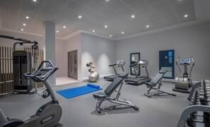 Ein modernes Fitnessstudio mit unterschiedlichen Trainingsgeräten, darunter Laufbänder, Crosstrainer und Kraftgeräte.