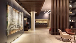 A modern lobby with a large abstract painting, a reception desk, and a seating area with a patterned rug.