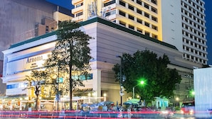 A high-rise hotel with a modern design, featuring a prominent vertical structure and a lower section with a visible entrance. - Arnoma Grand (Bangkok)