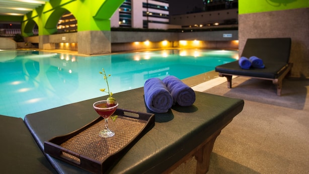 A poolside lounge with a bar area, a lounge chair, and a lifebuoy on the wall. - Arnoma Grand (Bangkok)
