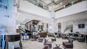 A spacious lobby with a grand piano, comfortable seating, and a staircase. - Arnoma Grand (Bangkok)
