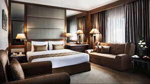 A hotel room with a large bed, a sofa, a desk, and a mirror. - Arnoma Grand (Bangkok)