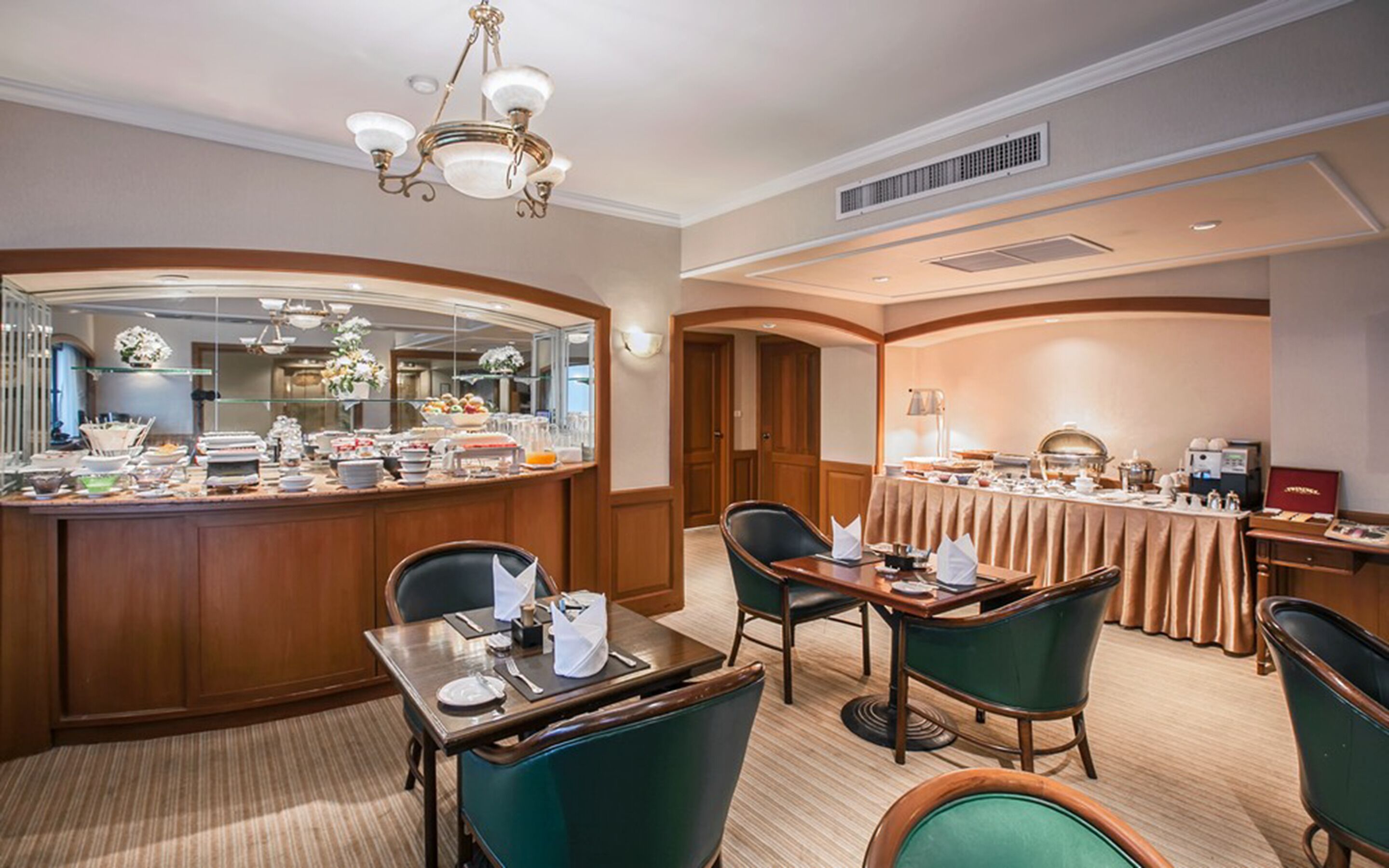 A hotel dining area with a buffet, a bar, and seating arrangements.