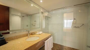 Une salle de bain avec une douche à parois de verre, un lavabo avec un miroir et un porte-serviettes.
