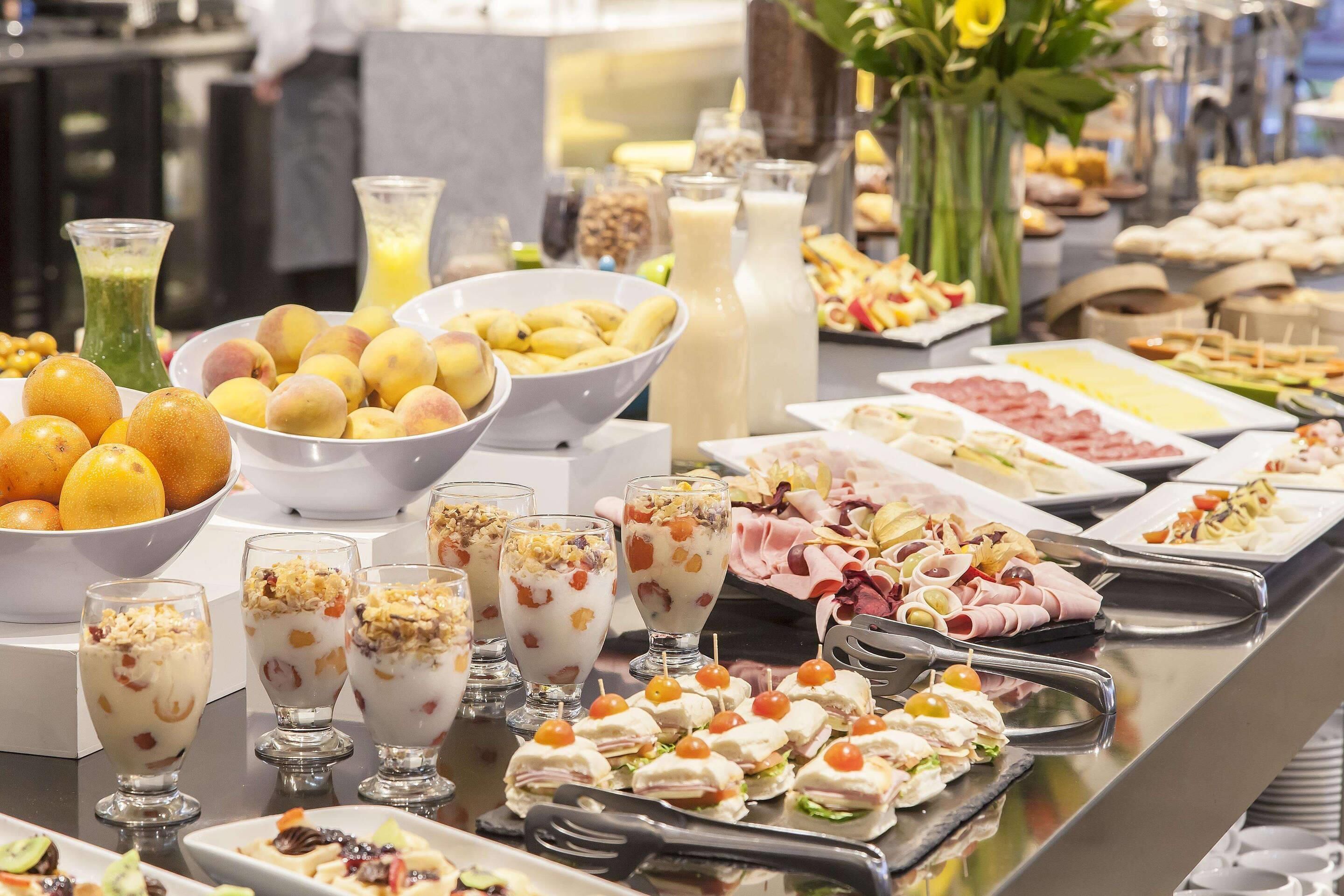 Un buffet proposant une variété de plats, notamment des fruits, des fromages et des sandwichs.
