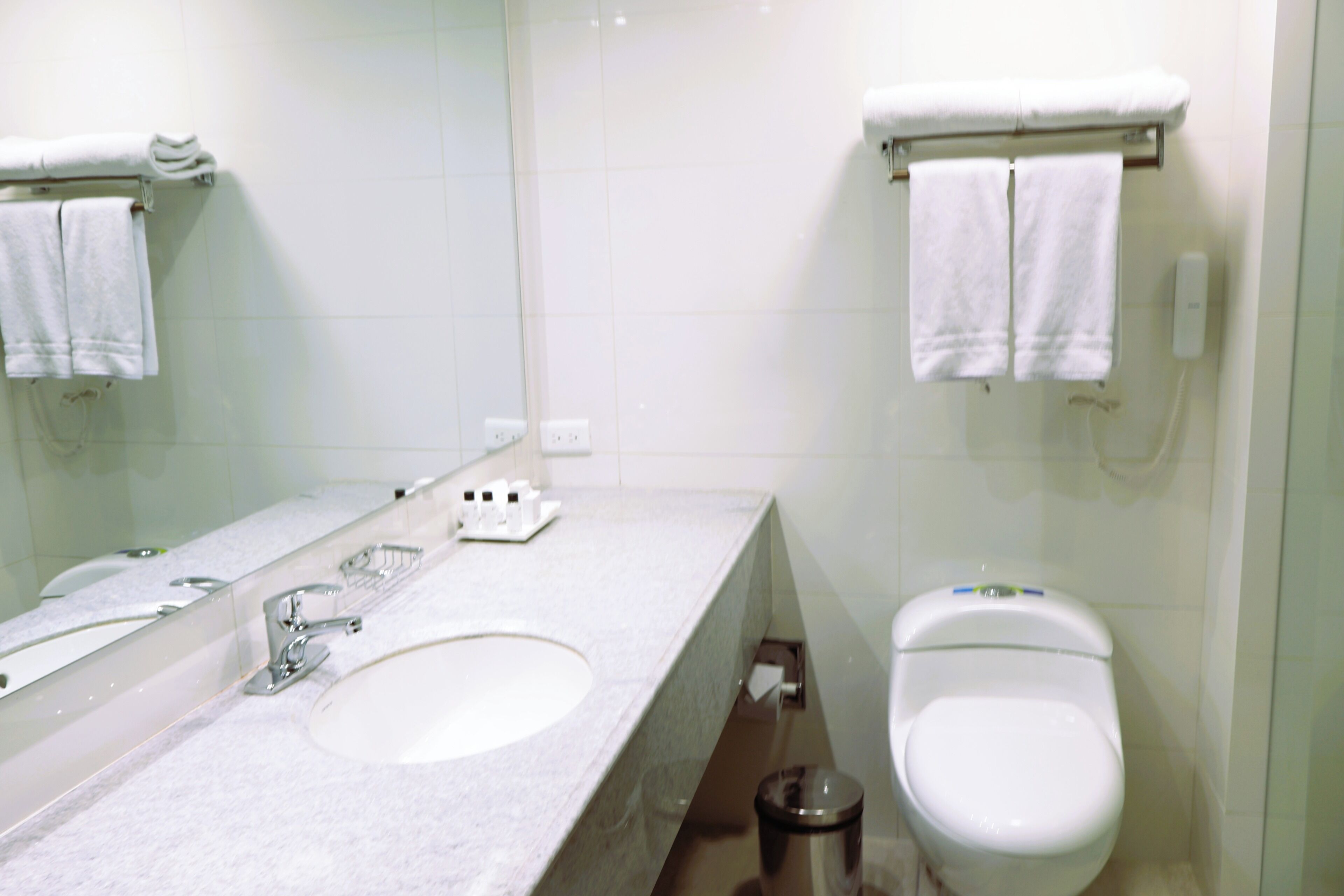 Ein Badezimmer mit einem Doppelwaschbecken, einer Toilette und zwei Handtüchern, die an der Wand hängen.