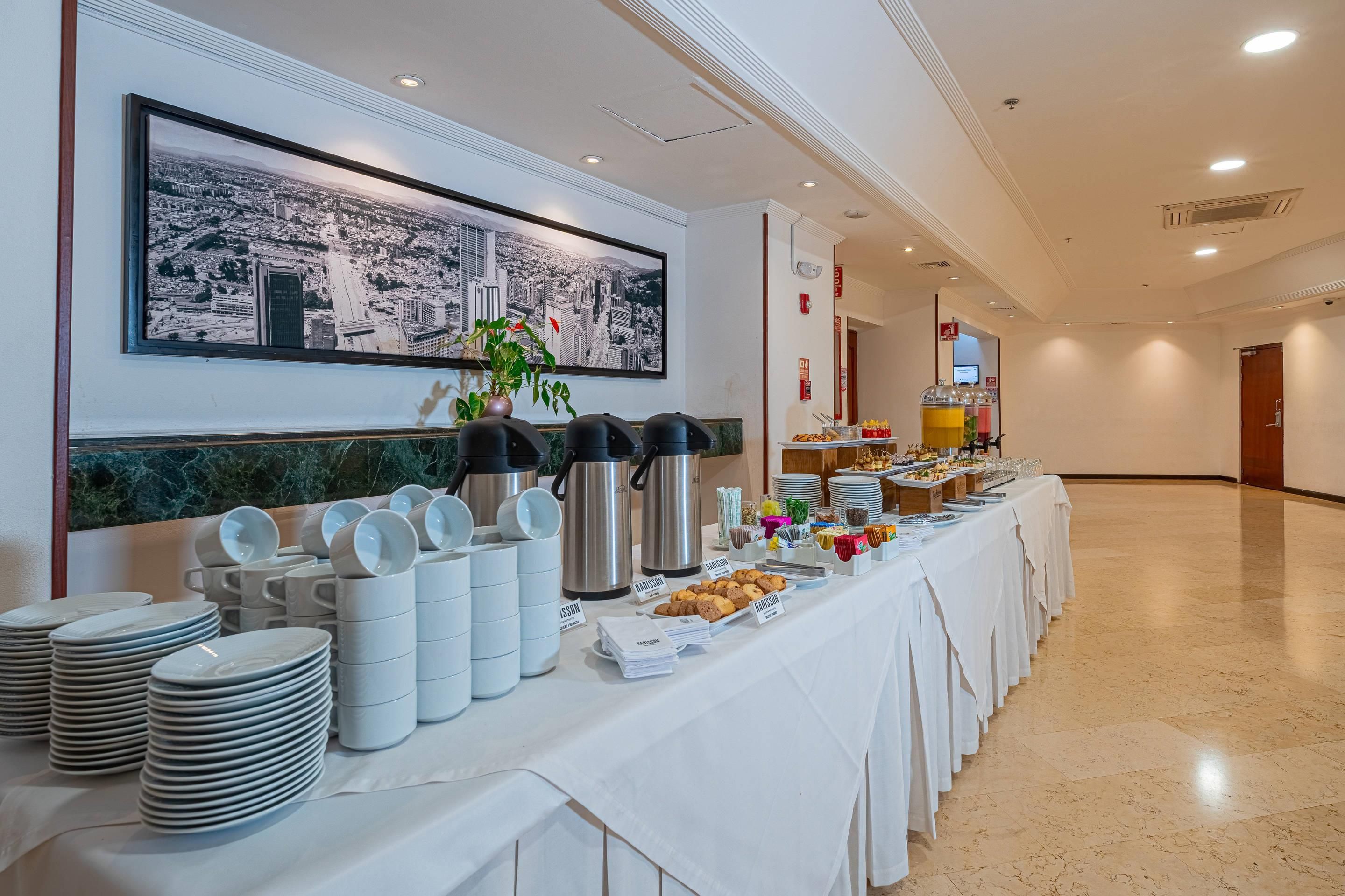 Una mesa de buffet con cafeteras, platos y diversos alimentos.