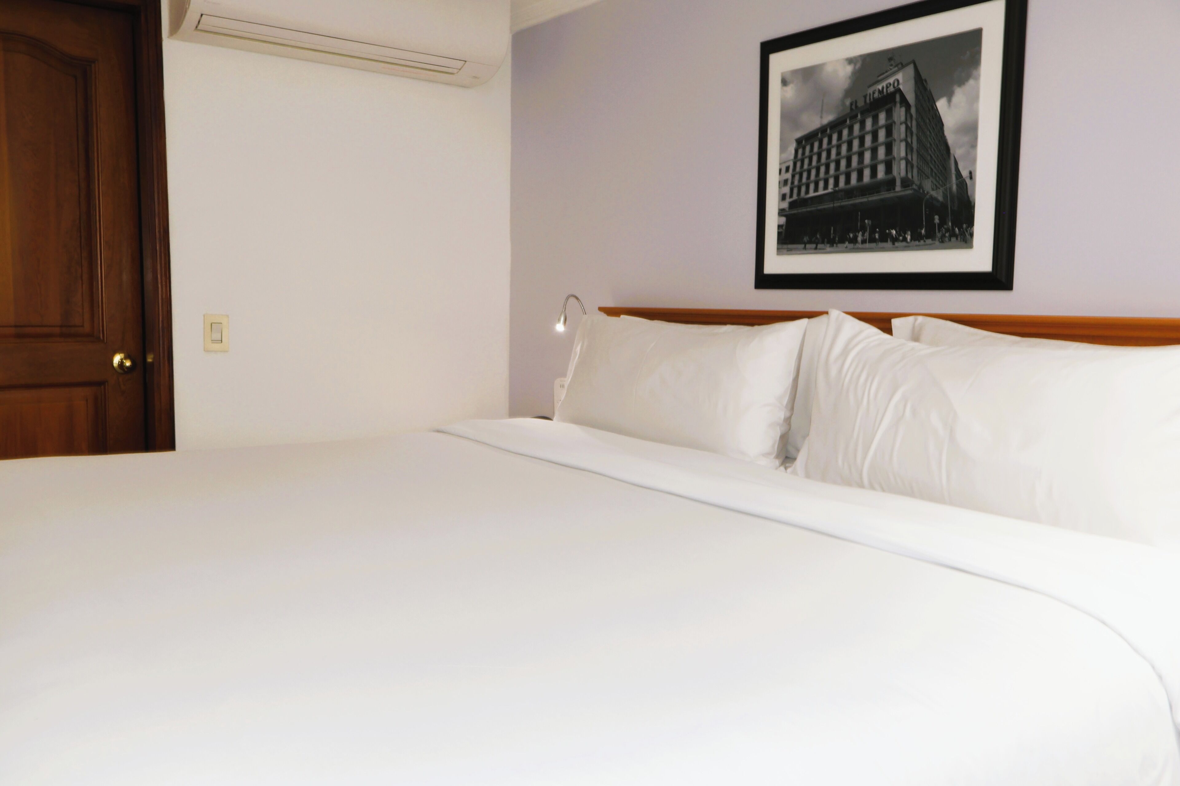 Una cama bien hecha en una habitación de hotel con un cuadro en la pared.