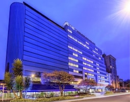 A multi-story hotel with a modern design, featuring a prominent vertical structure on the left and a flat facade with evenly spaced windows.