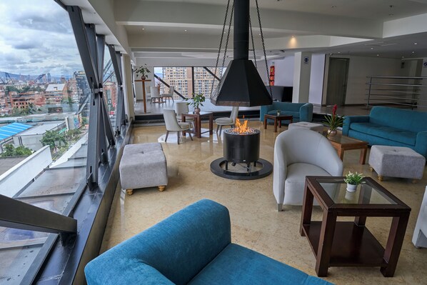 Una sala de estar moderna con un ventanal grande, un brasero colgante y vistas a la ciudad.