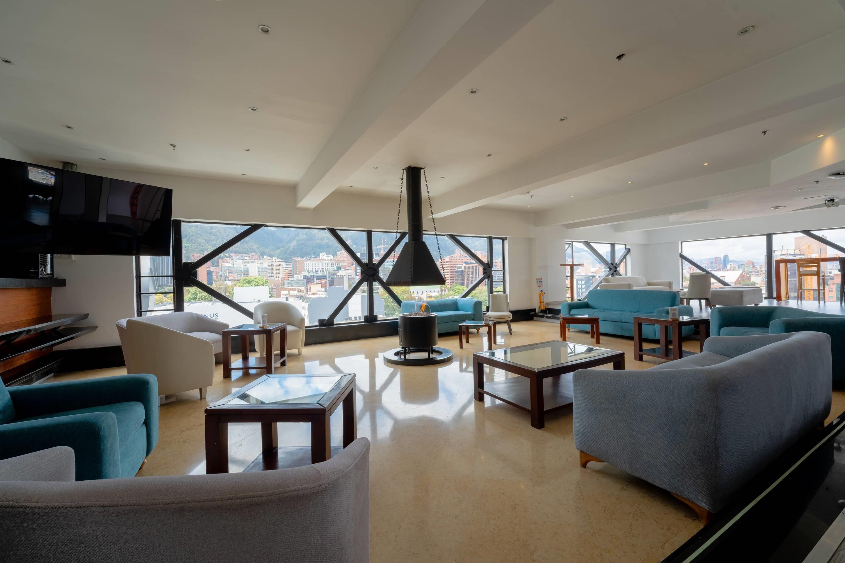 A spacious living room with a large window, a fireplace, and modern furniture.