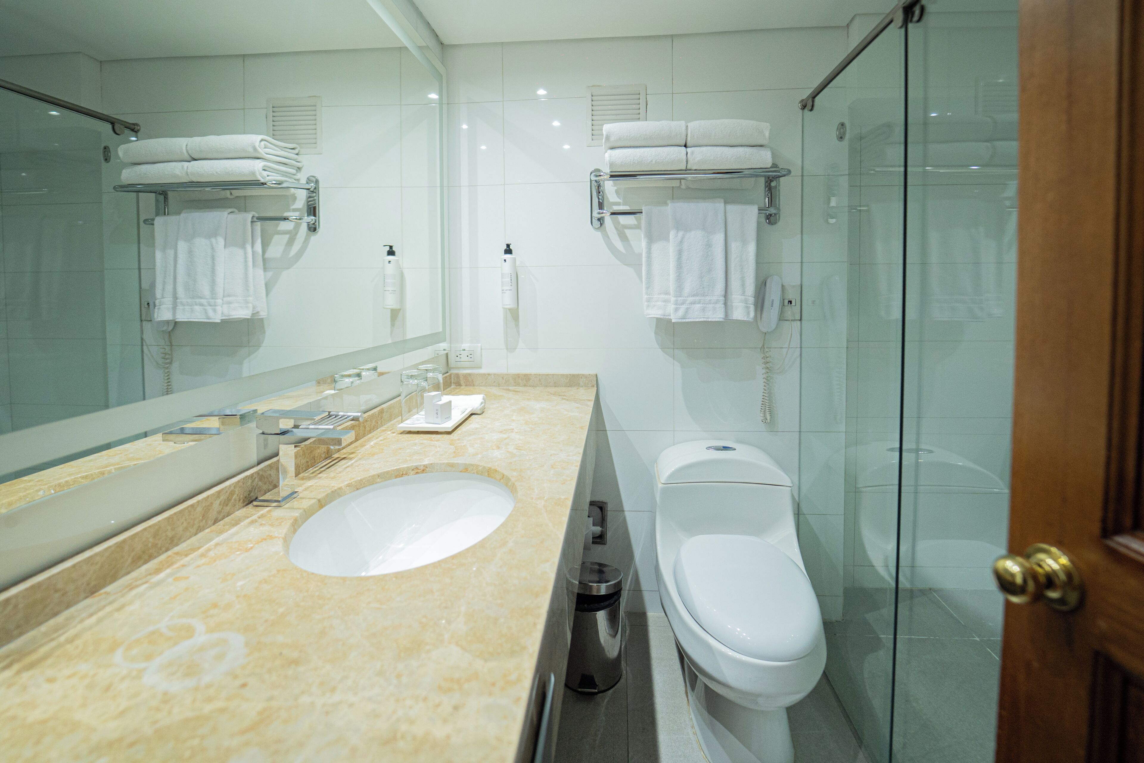 Un baño moderno con lavamanos doble, inodoro, cabina de ducha de vidrio y un espejo grande.