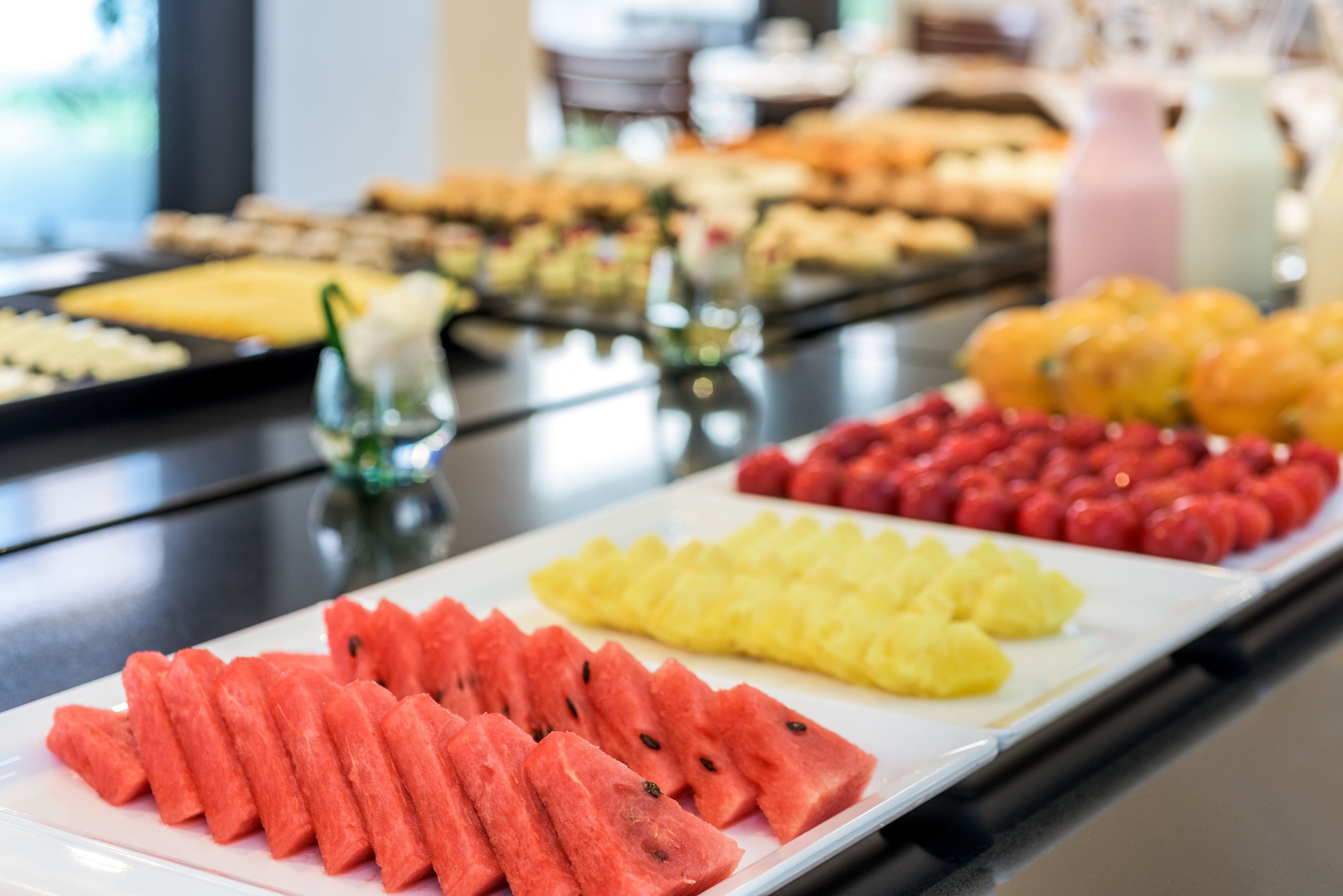 A buffet with watermelon, pineapple, and strawberries.