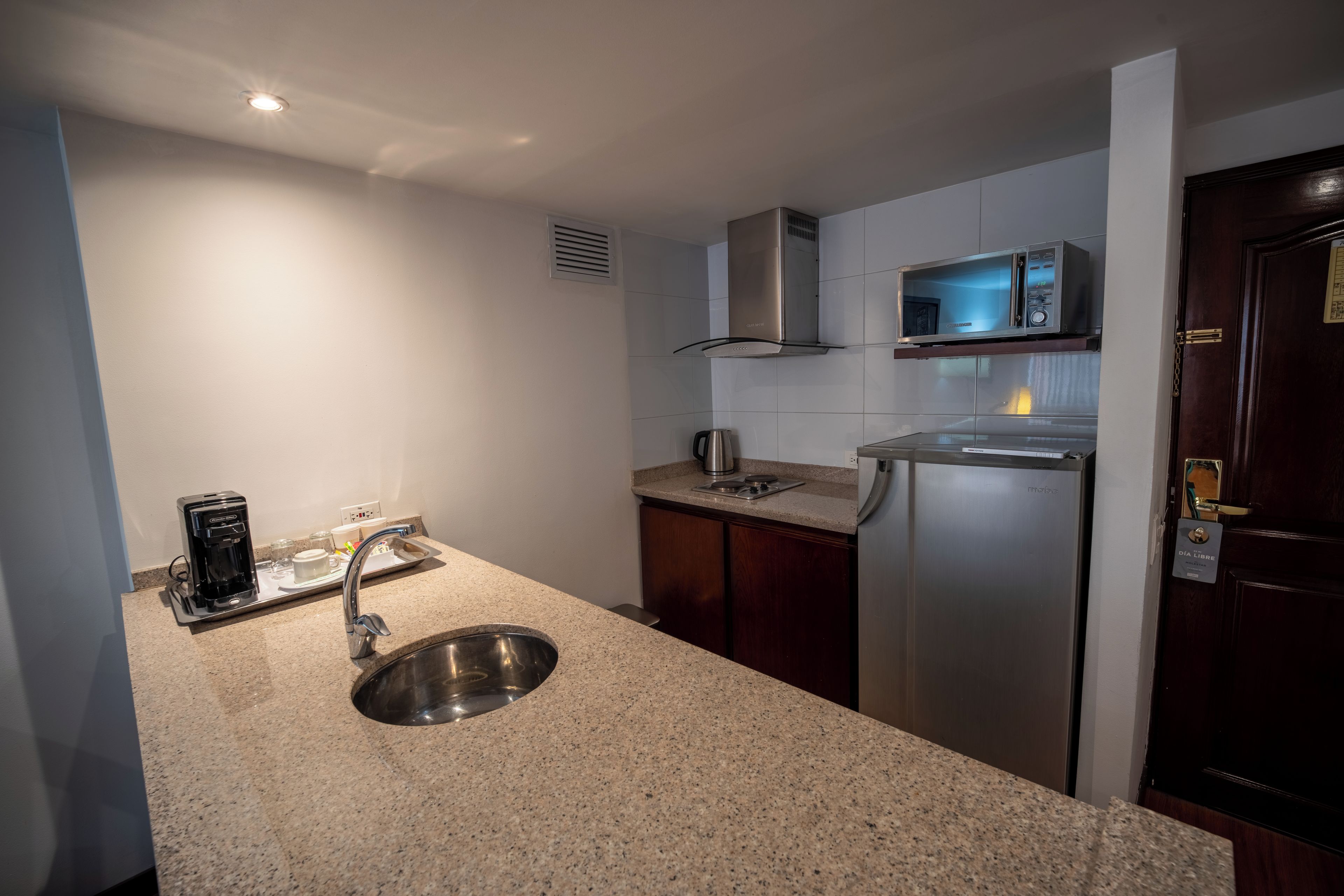 A modern kitchen with a stainless steel sink, a coffee maker, and a microwave.
