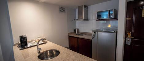 A modern kitchen with a stainless steel sink, a coffee maker, and a microwave.