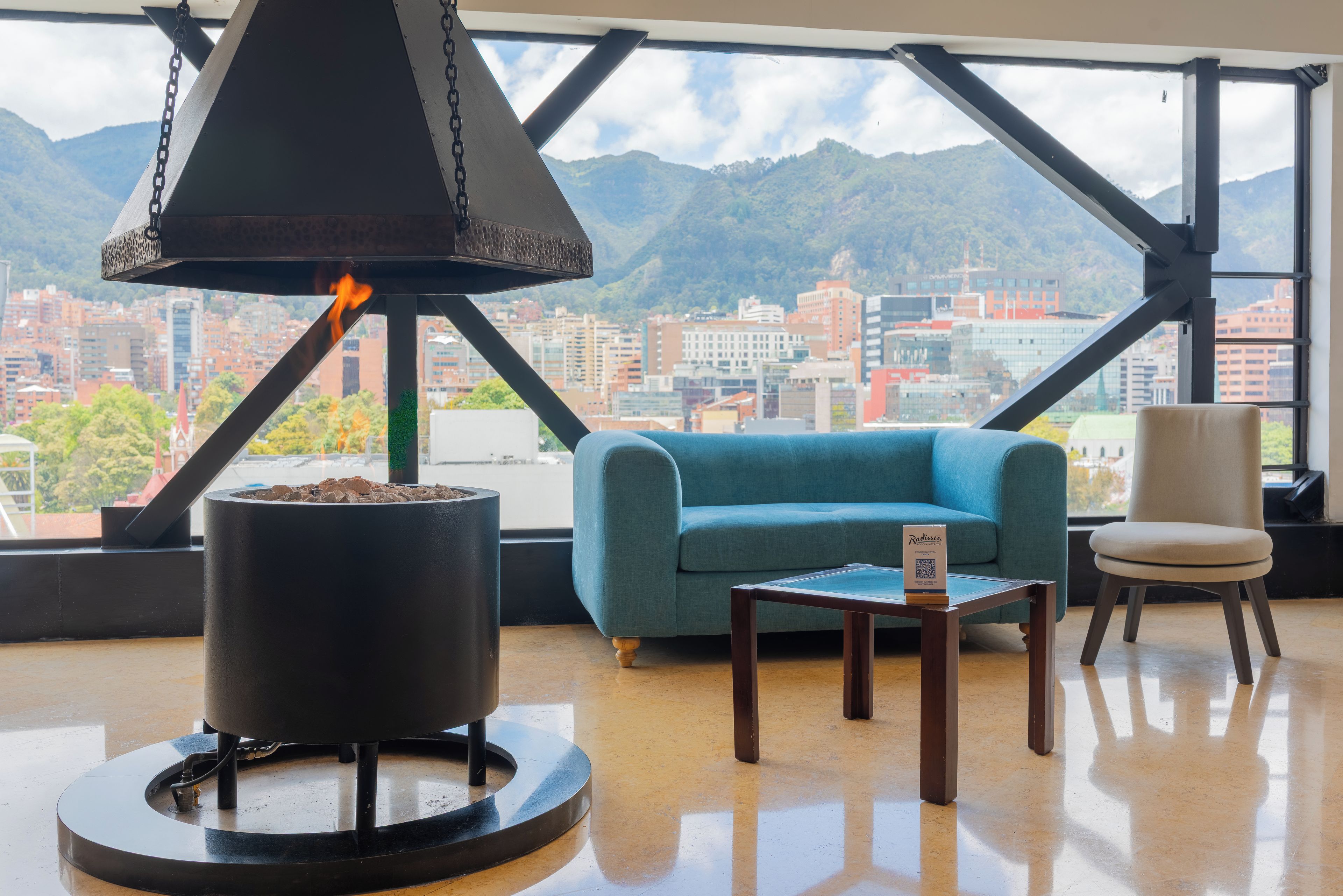 Una habitación con chimenea, un sofá azul, una mesita y una silla.