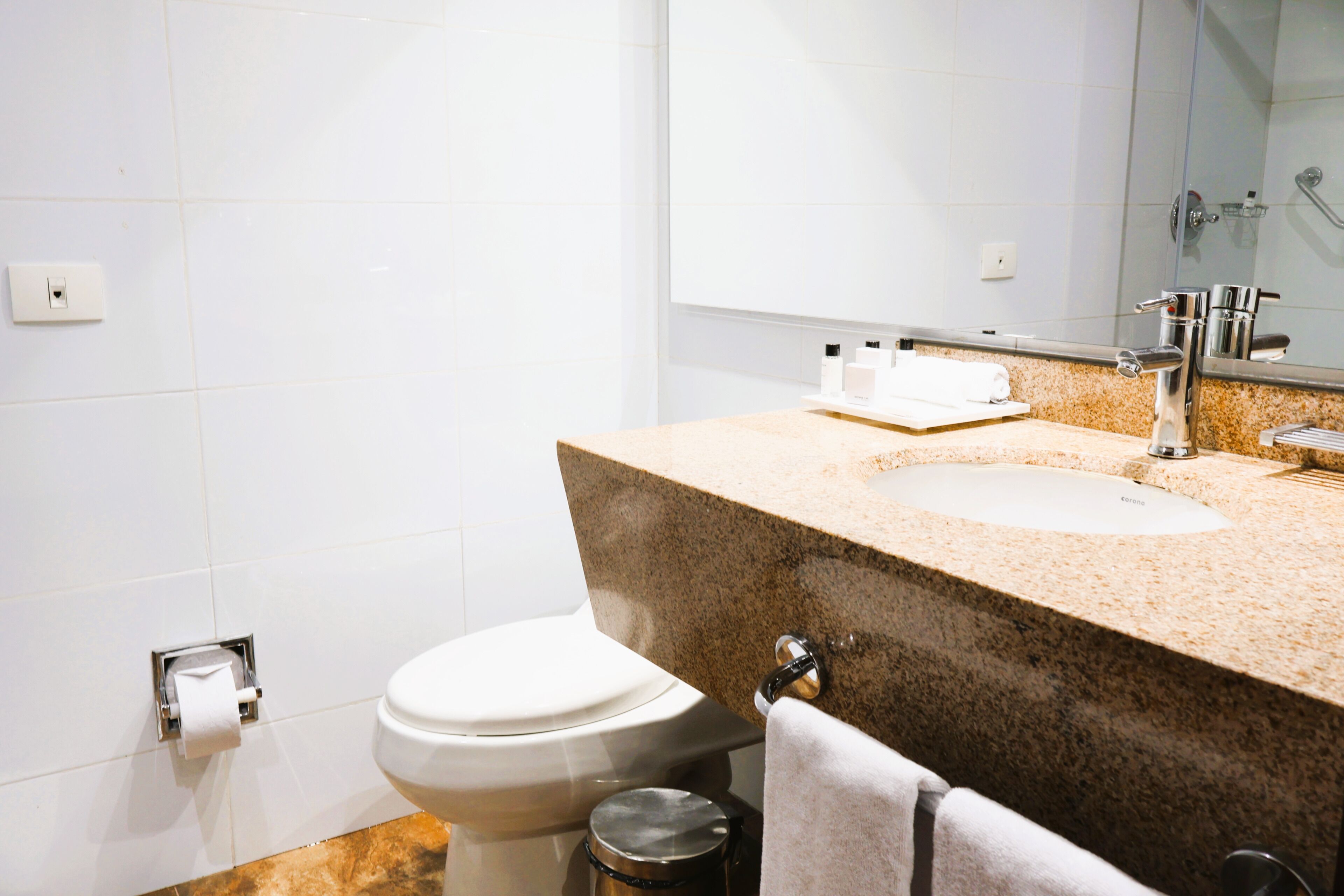 Un baño con inodoro, lavamanos, espejo y toallero.