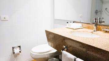 Un baño con inodoro, lavamanos, espejo y toallero.
