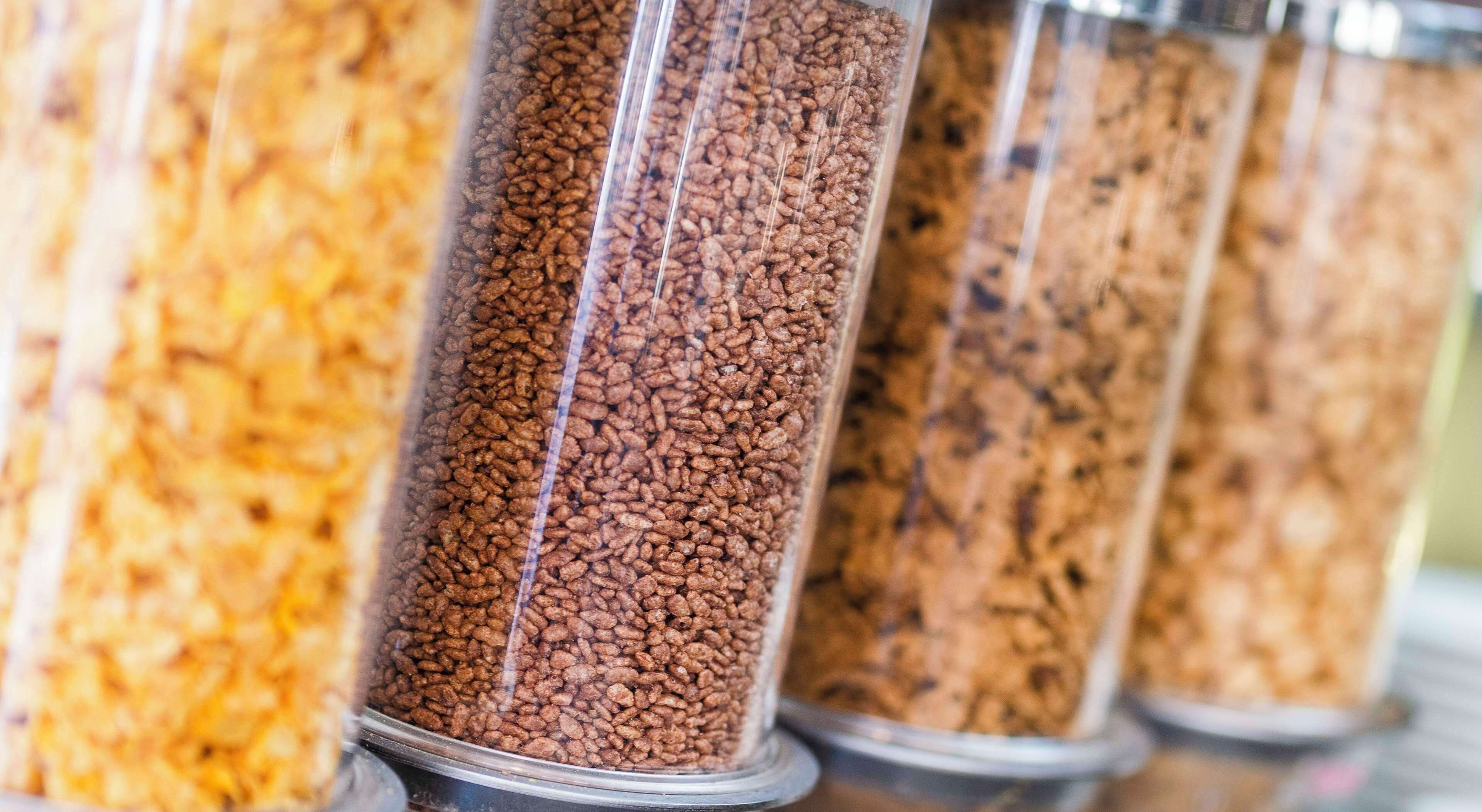 A row of cylindrical containers filled with different types of grains or seeds.